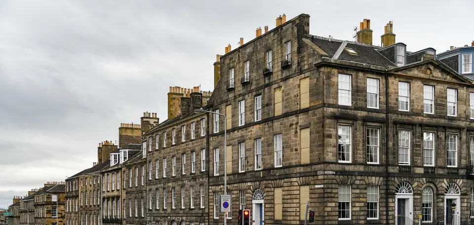 Slate roofs, dormer windows and chimney stacks above a long sandstone terrace in Edinburgh’s New Town.