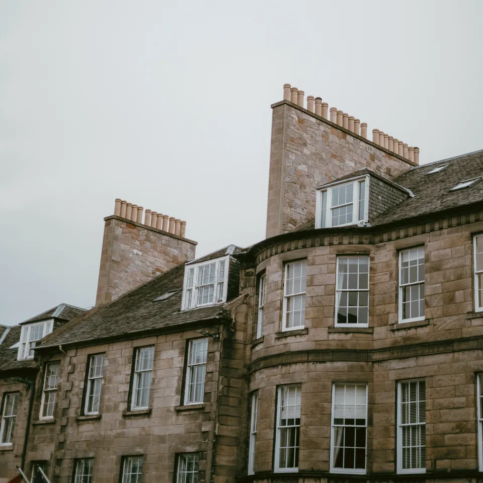 Slate roofs, dormer windows and sandstone chimney stacks on an Edinburgh terrace.